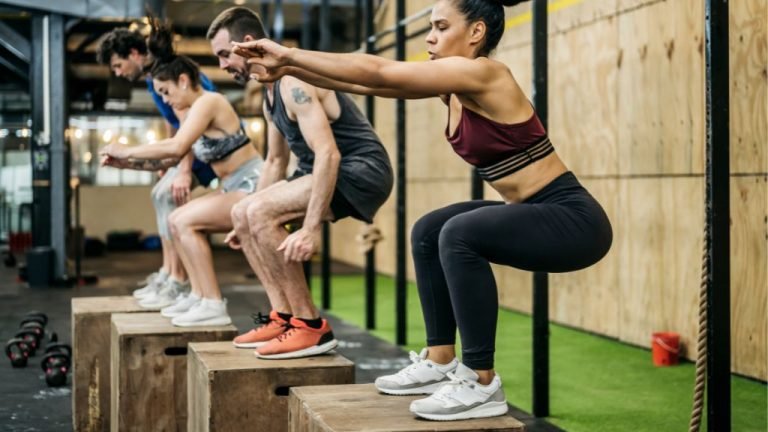 Atletas de crossfit com tênis de crossfit Reebok fazendo salto em caixa.