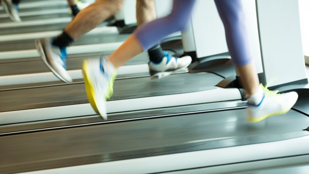 Enquadramento da perna de duas pessoas a correr na esteira